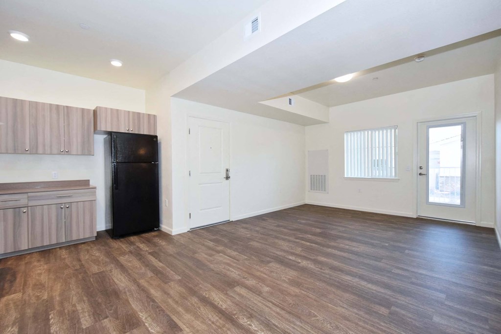 the living room and kitchen of an apartment with a refrigerator