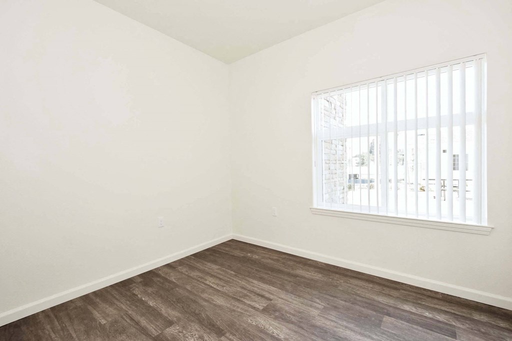 an empty room with a window and wood flooring