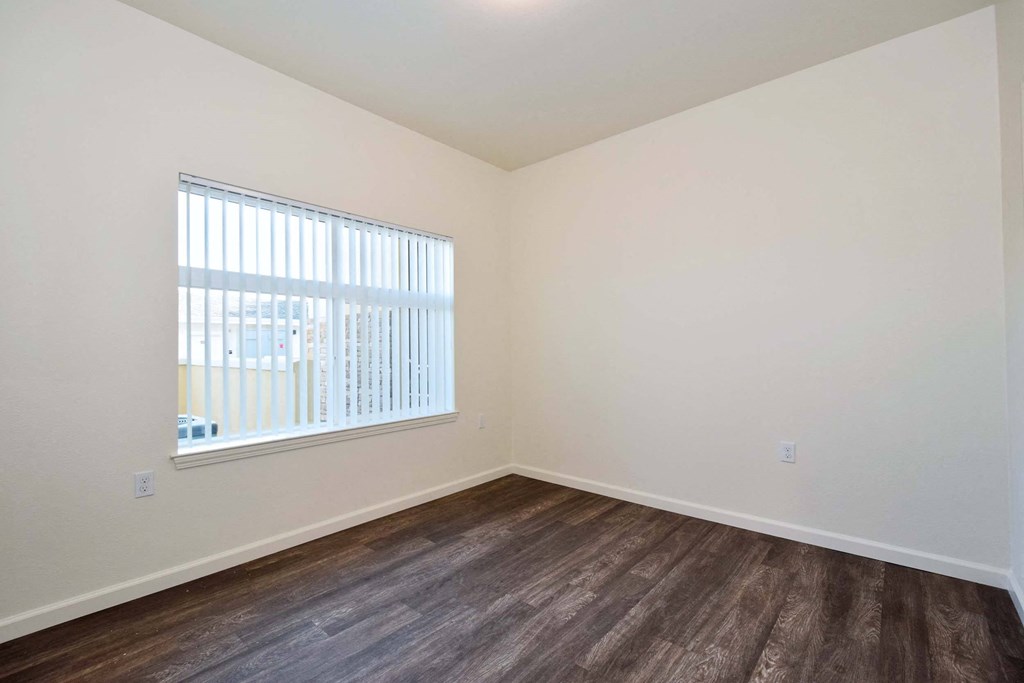 a bedroom with wood flooring and a window