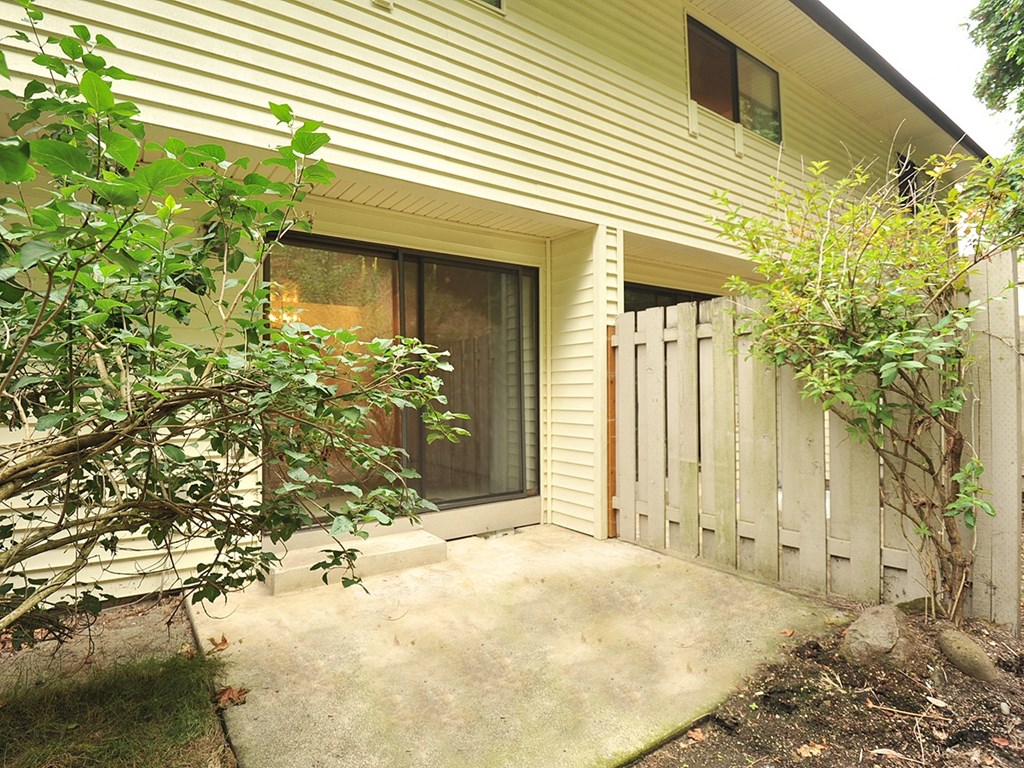 the front porch of the house has a walkway and a fence