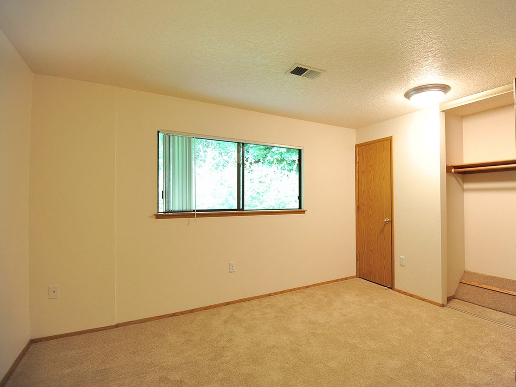 an empty bedroom with a window and a closet
