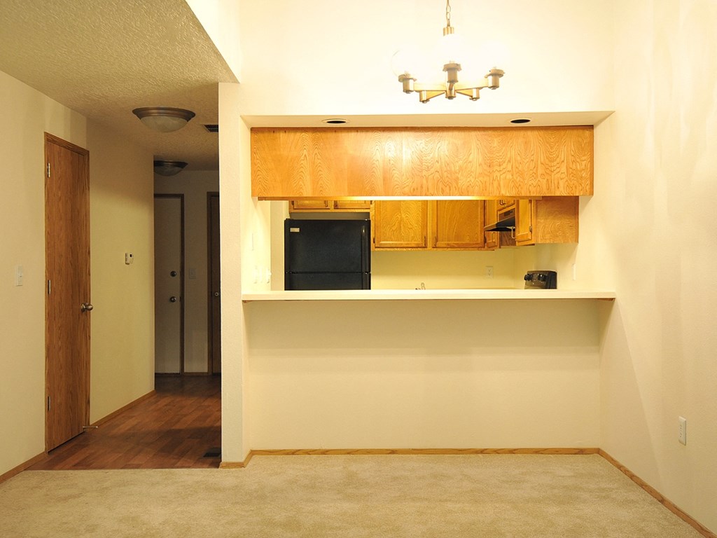 a empty kitchen with a counter and a black refrigerator