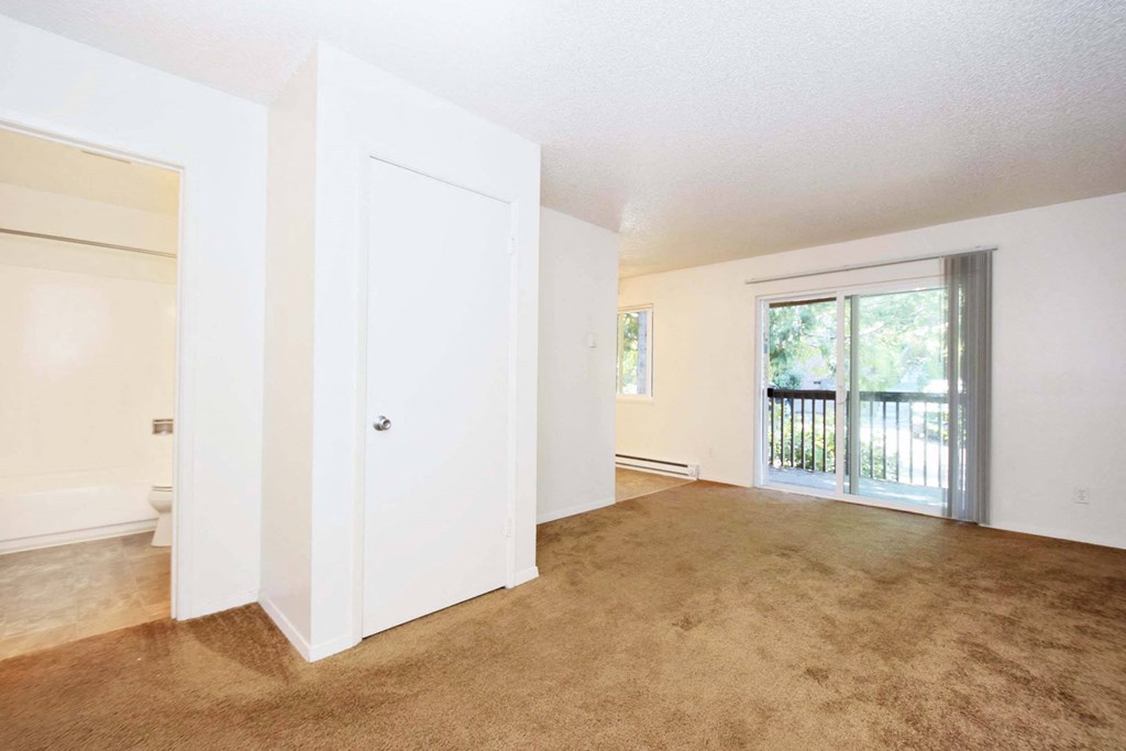 an empty living room with a door to a balcony