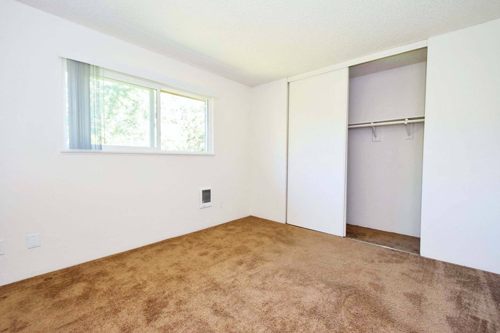 an empty room with a window and a closet