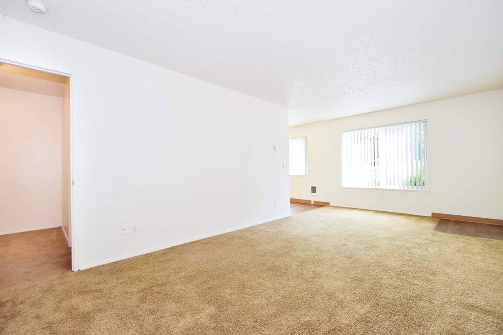 an empty living room with white walls and carpet