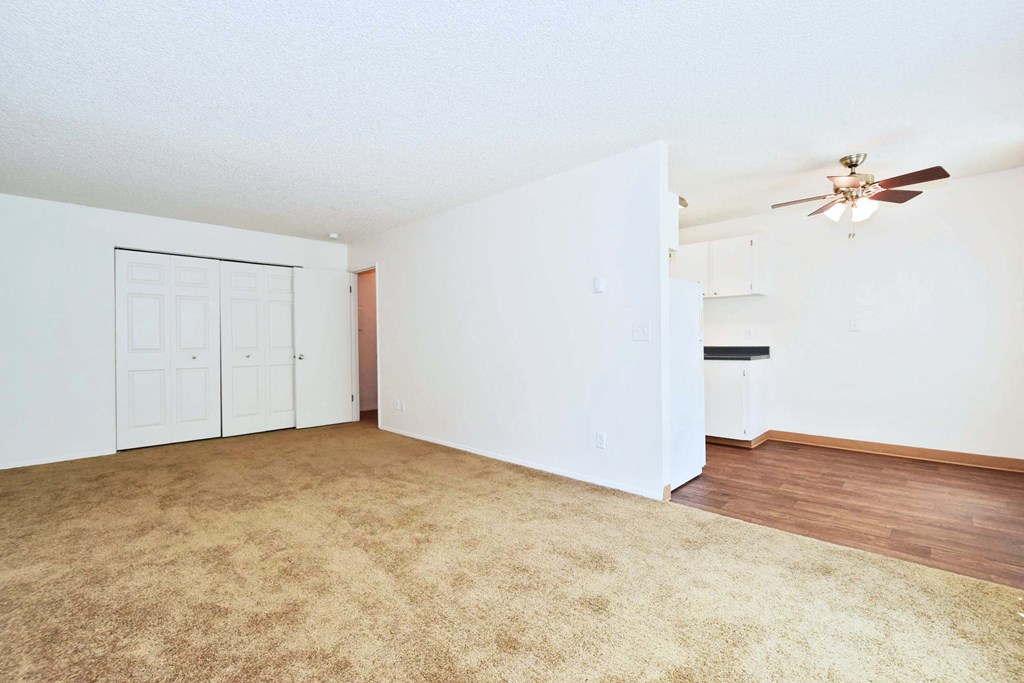 an empty living room with white walls and a ceiling fan
