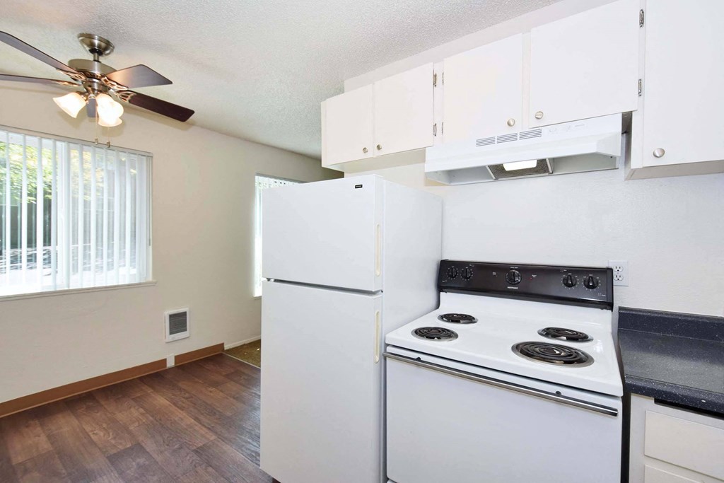 an empty kitchen with white appliances and a window