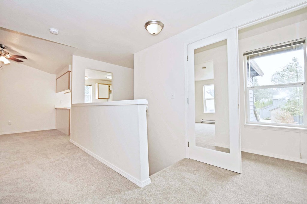 a view of a hallway with white walls and a window