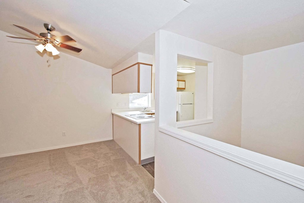 a renovated living room and kitchen with a ceiling fan