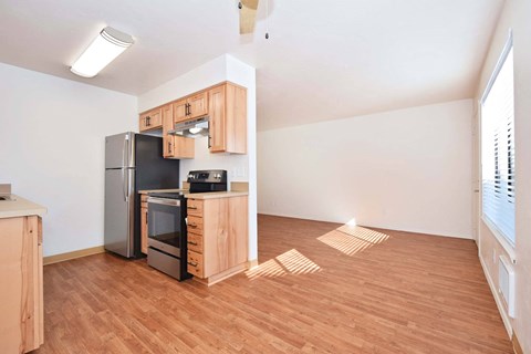 a kitchen and living room with wood floors and a refrigerator
