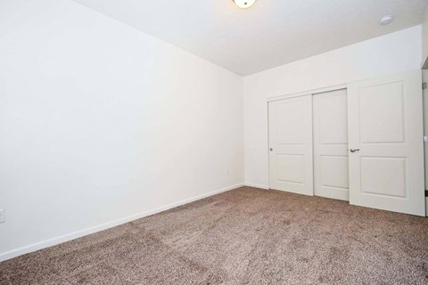 a bedroom with white walls and carpet and two doors