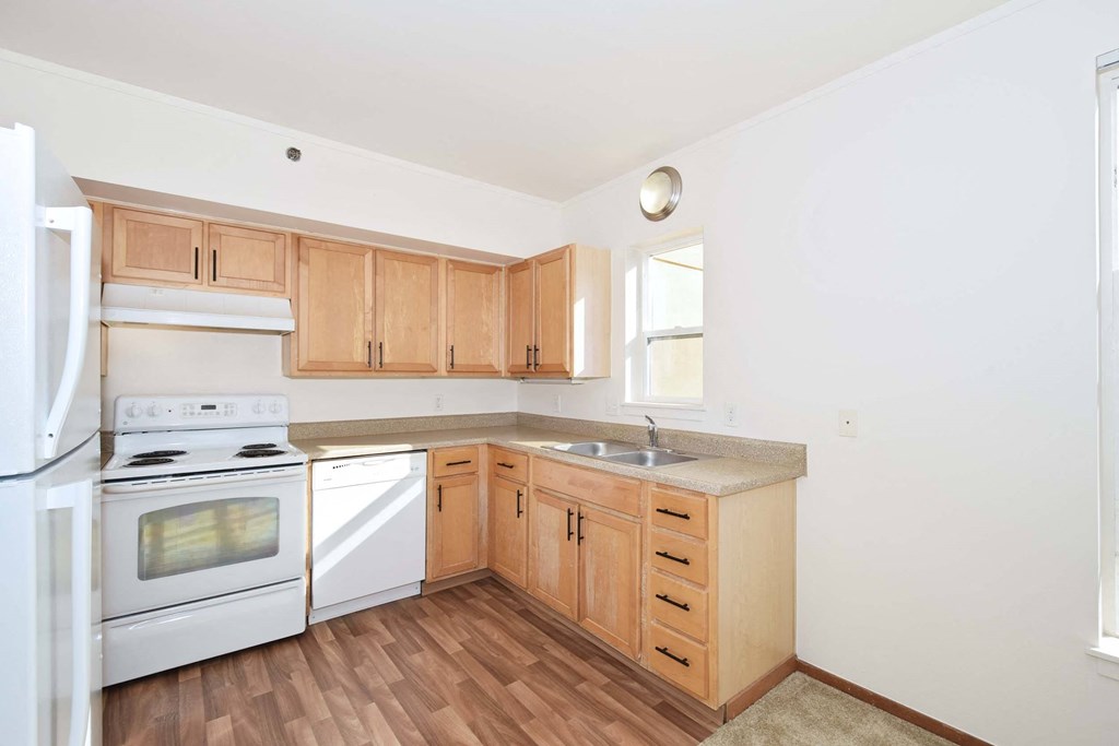 an empty kitchen with wooden cabinets and white appliances