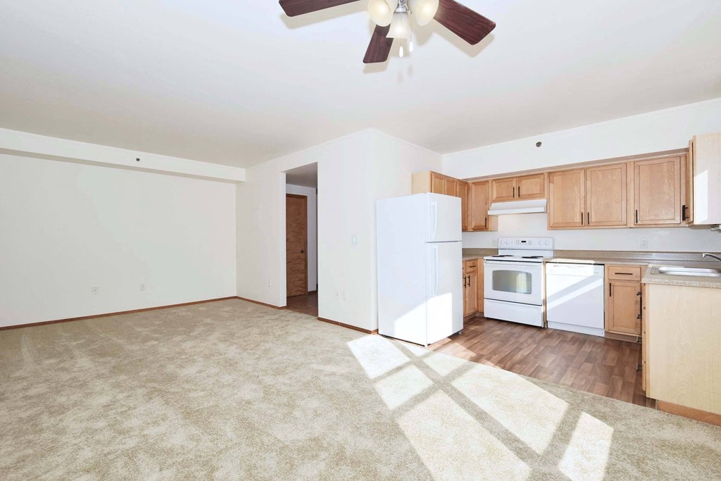 an empty kitchen with white appliances and wooden cabinets