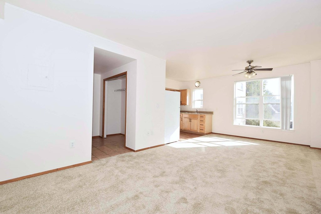 an empty living room with a ceiling fan and a window