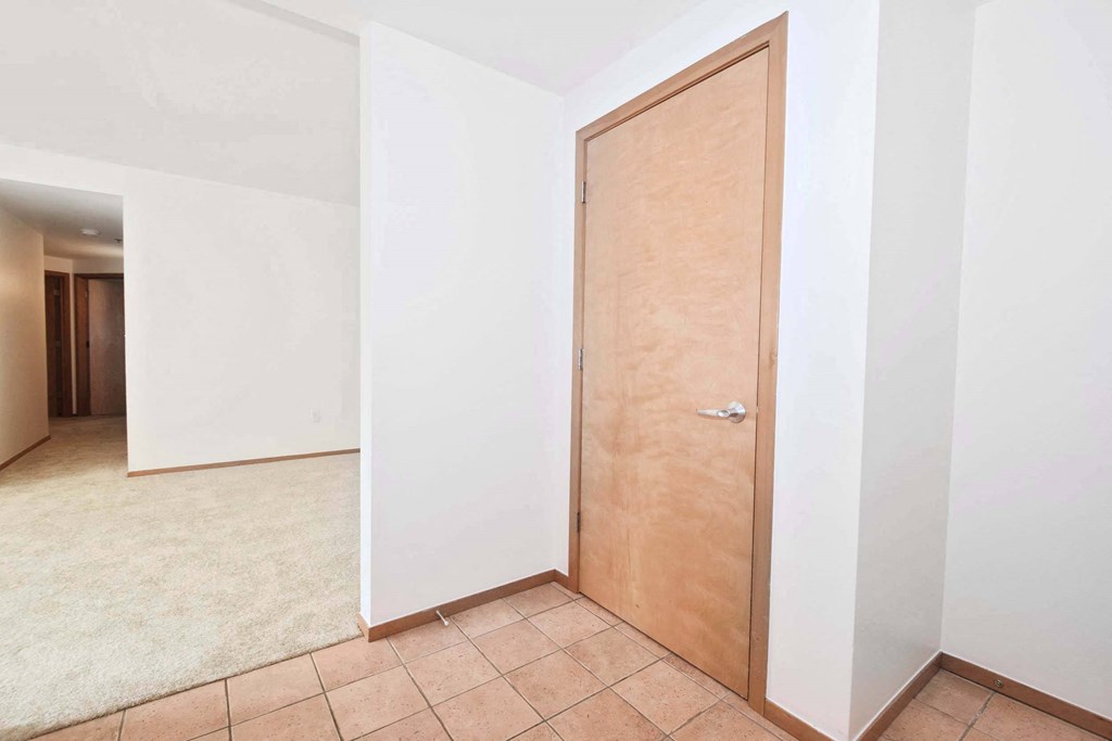 a empty room with a wooden door and a tiled floor