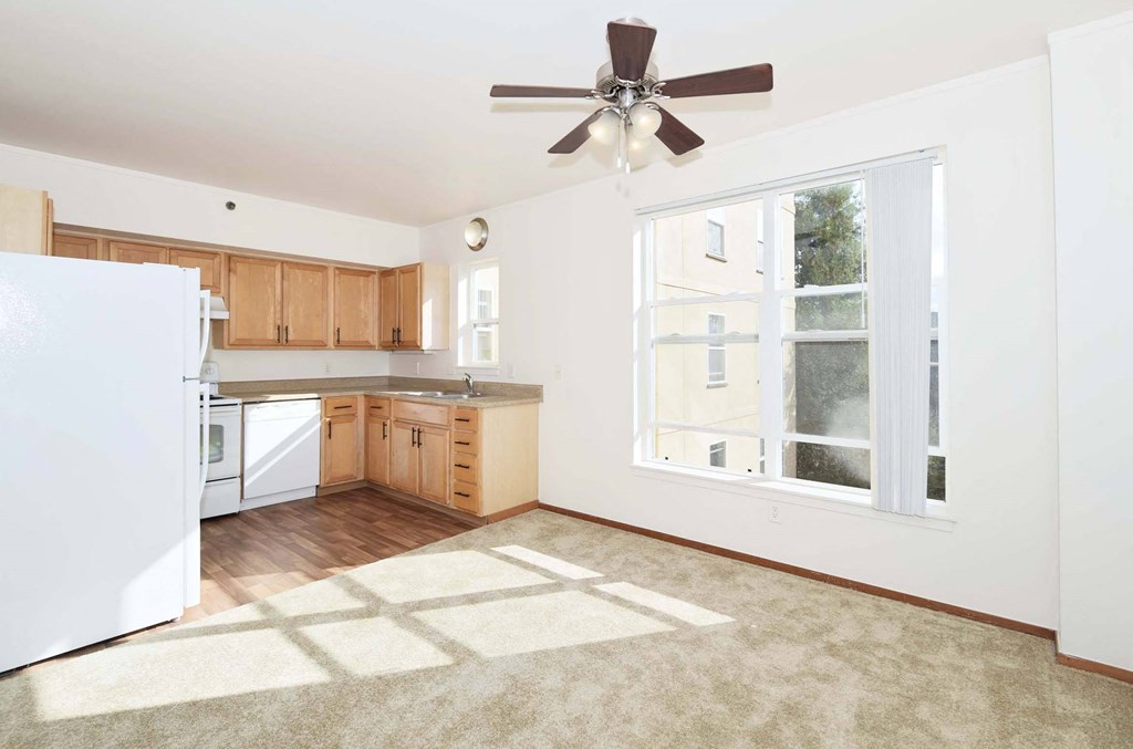 an empty kitchen with a ceiling fan and a window