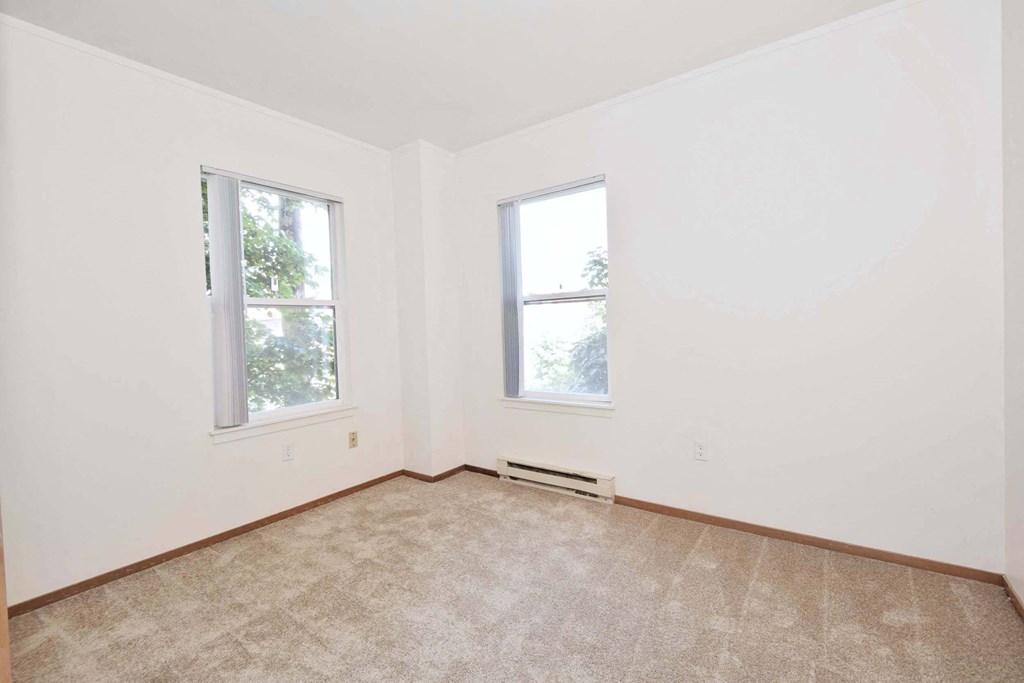 an empty room with two windows and a carpet