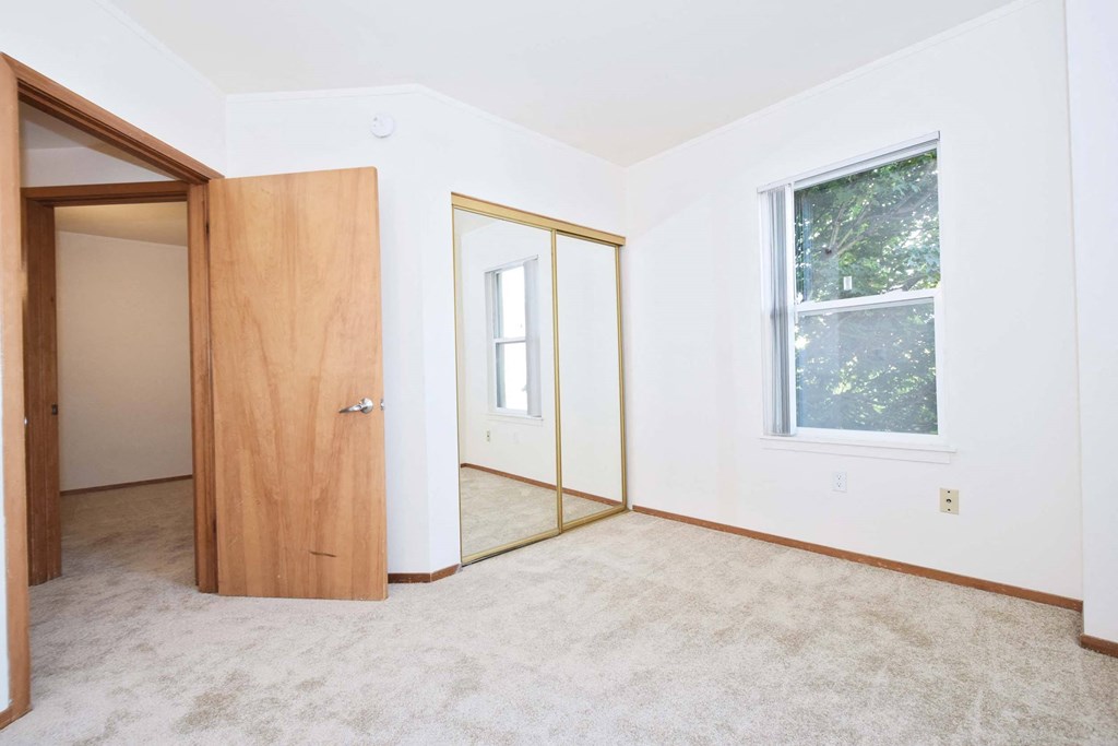 an empty room with a door to a closet and a window
