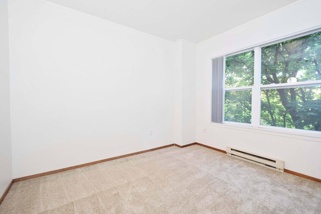 an empty room with a large window and carpet