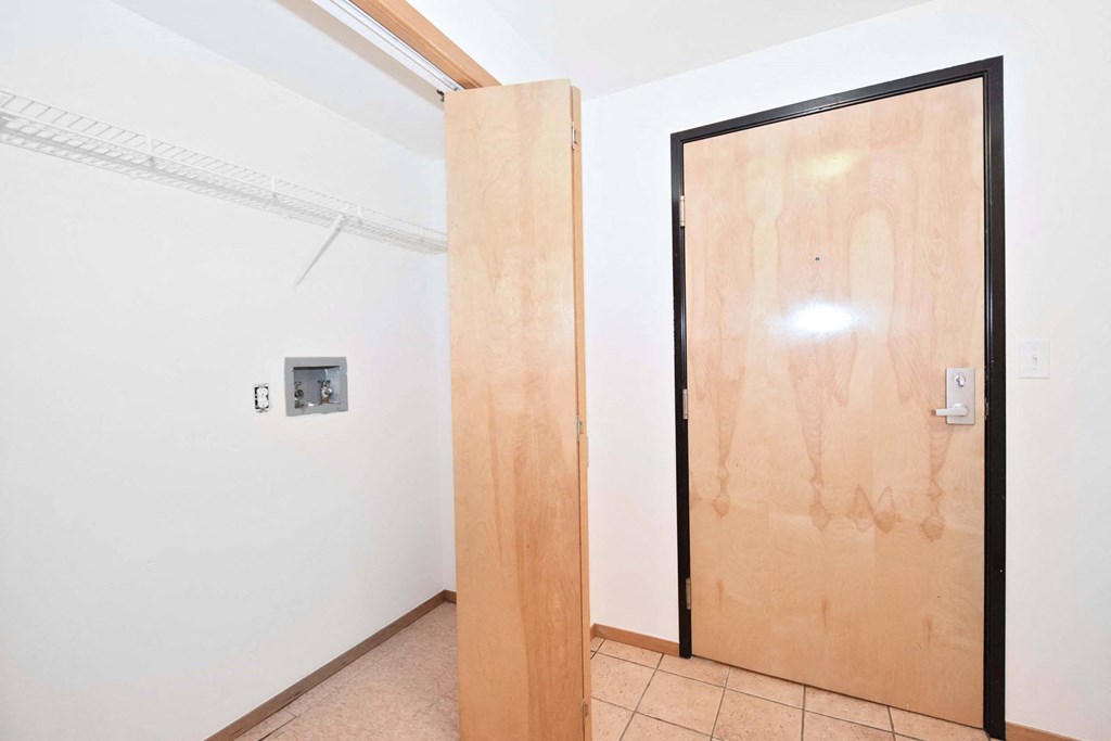 a wooden door in a white room with a tile floor