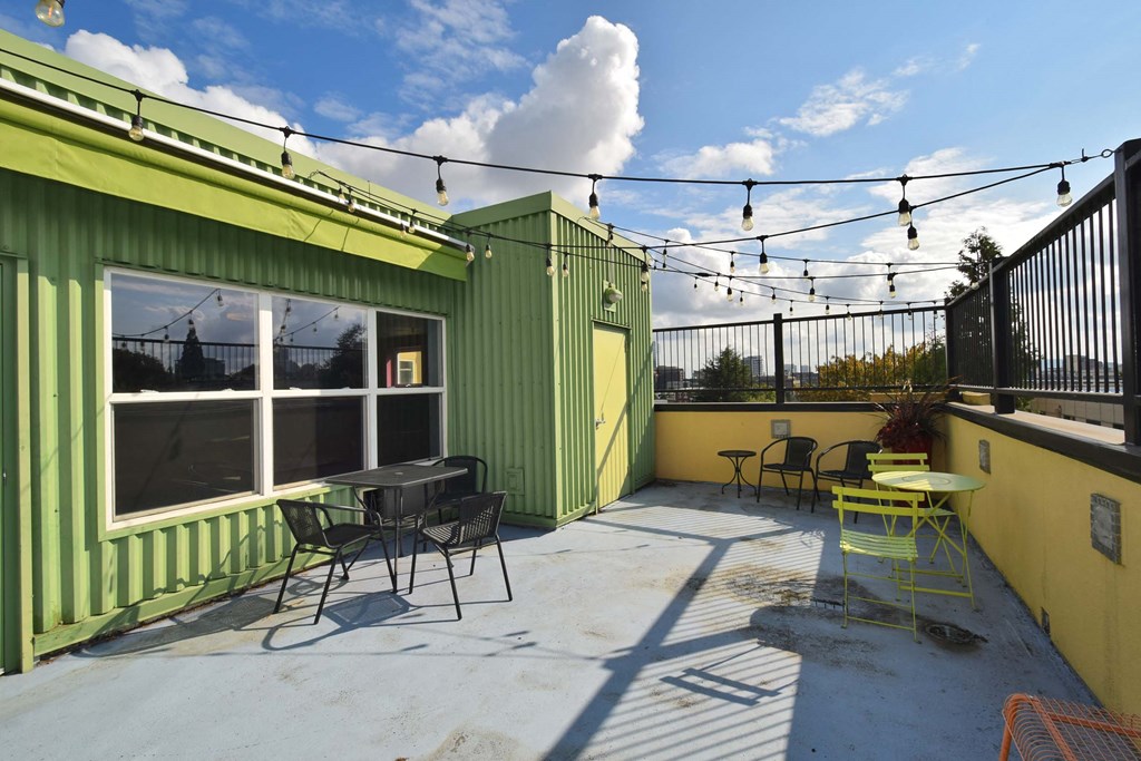 a patio with tables and chairs and a green building