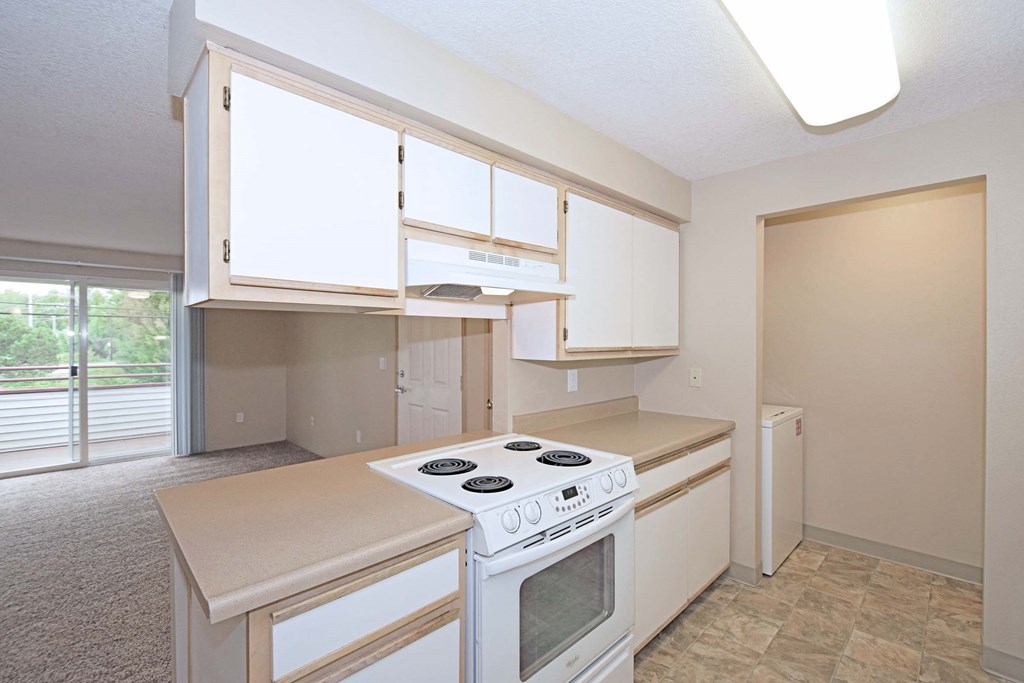 an empty kitchen with white appliances and white cabinets