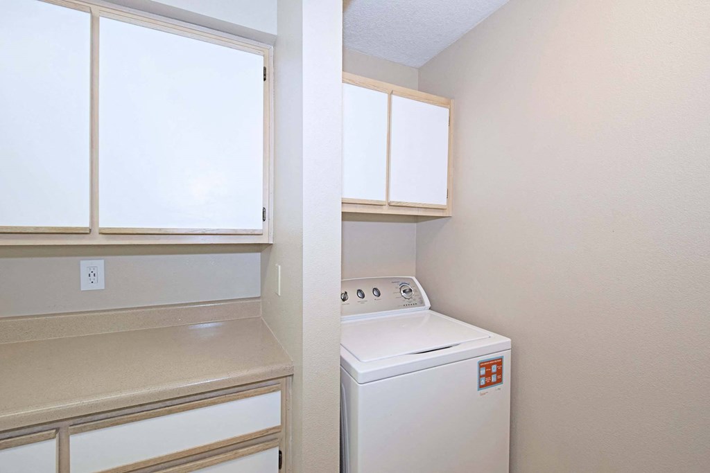 a laundry room with a washer and dryer and white cabinets