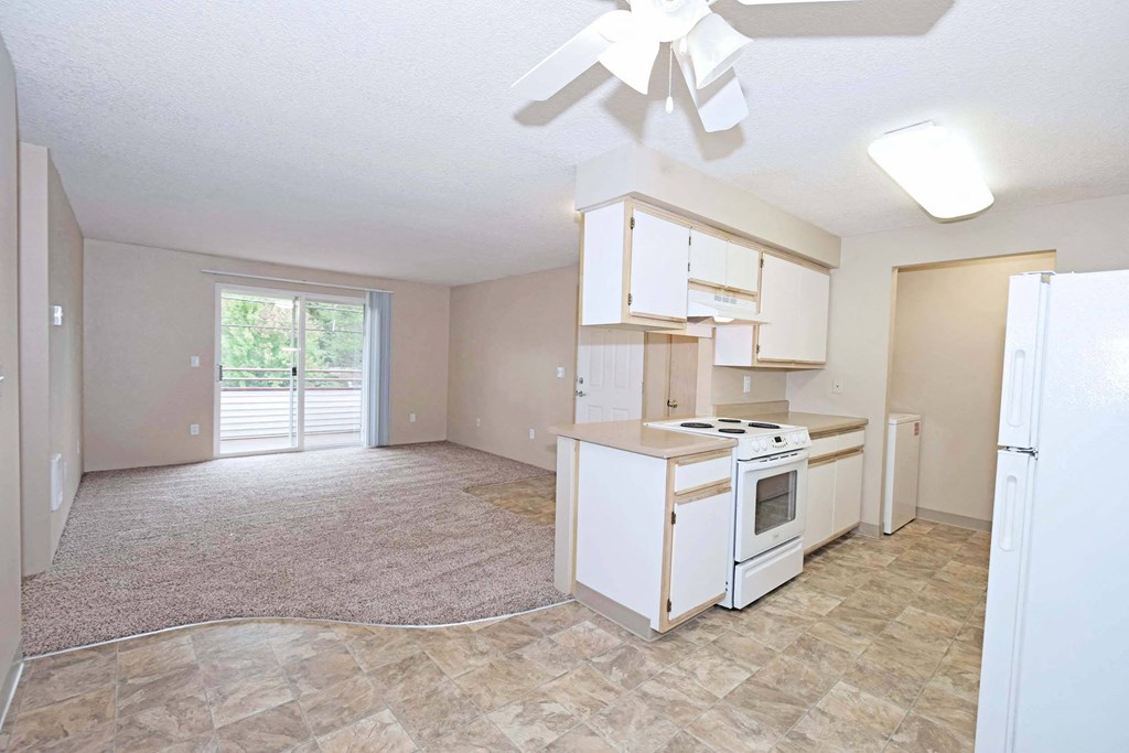 an empty kitchen and living room with a refrigerator and stove