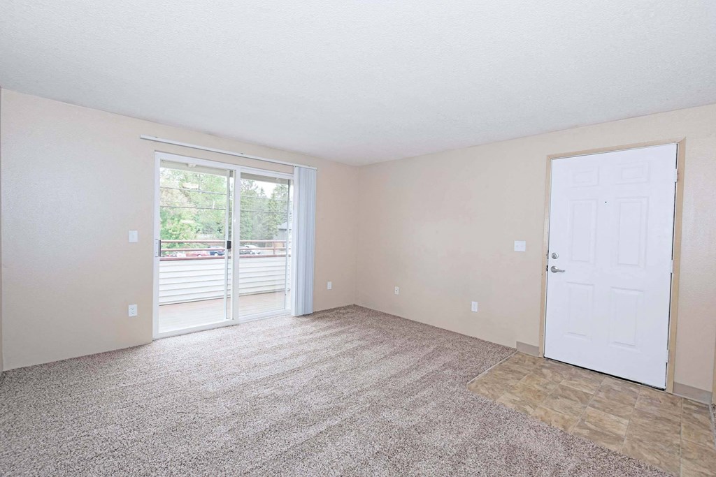 an empty living room with a door to a balcony