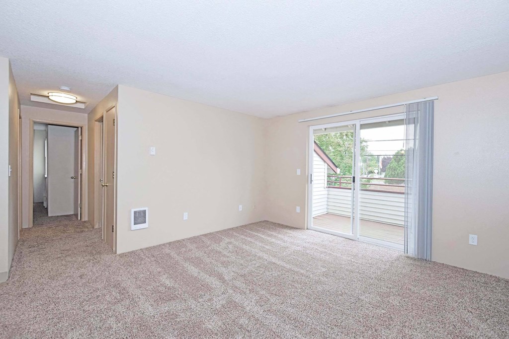 an empty living room with a sliding glass door to a balcony