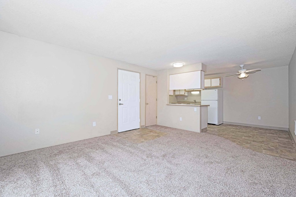 an empty living room and kitchen with a white door