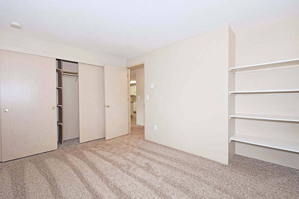 a bedroom with white walls and a closet and shelves