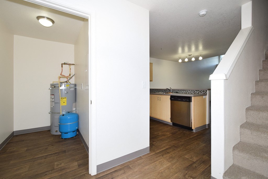 a view of a kitchen from the bottom of the stairs with a blue water heater