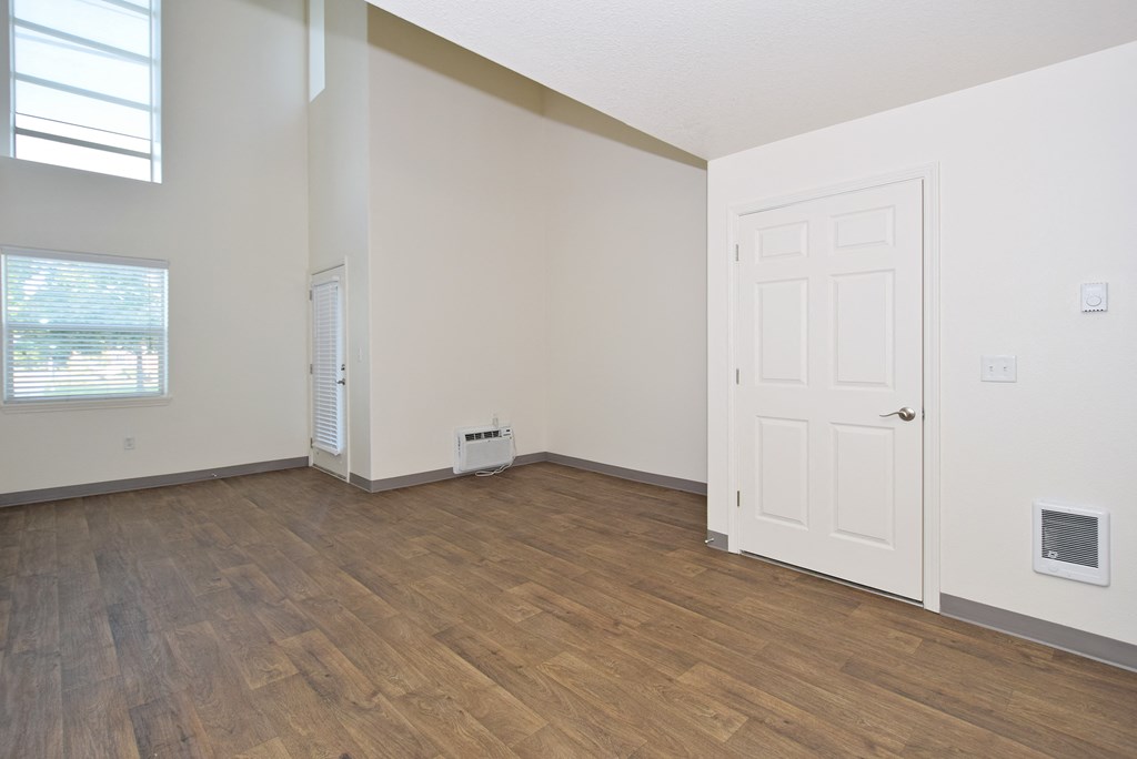 an empty living room with a white door and wood flooring