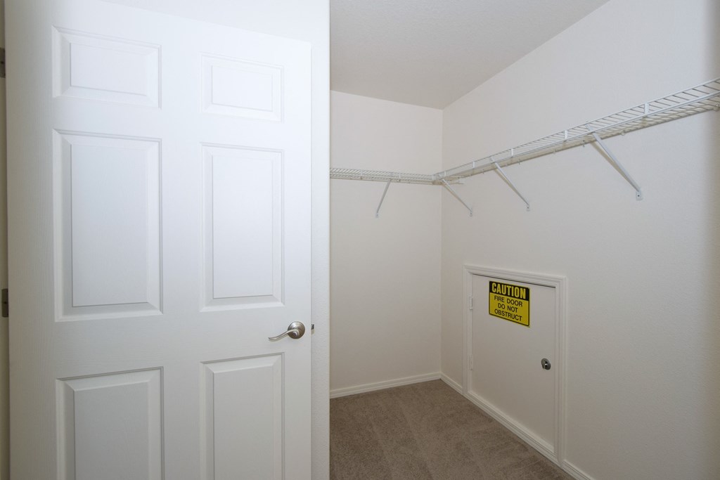 an empty closet with a white door and a white closet door to a white room