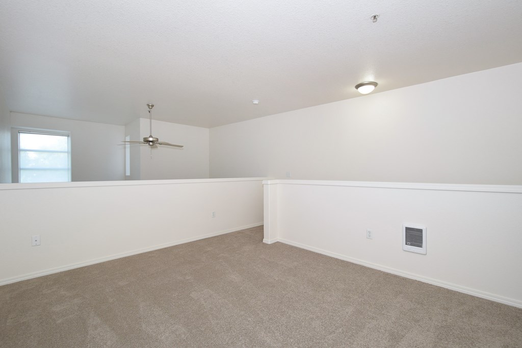 an empty living room with white walls and carpet and a window