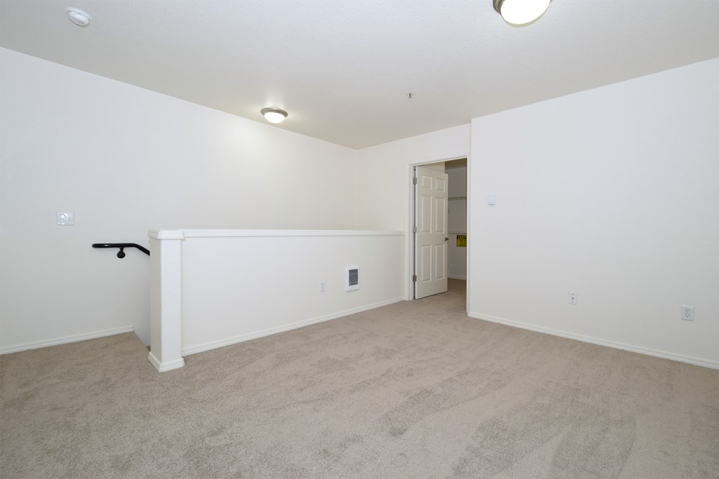 an empty living room with white walls and carpet and a white door