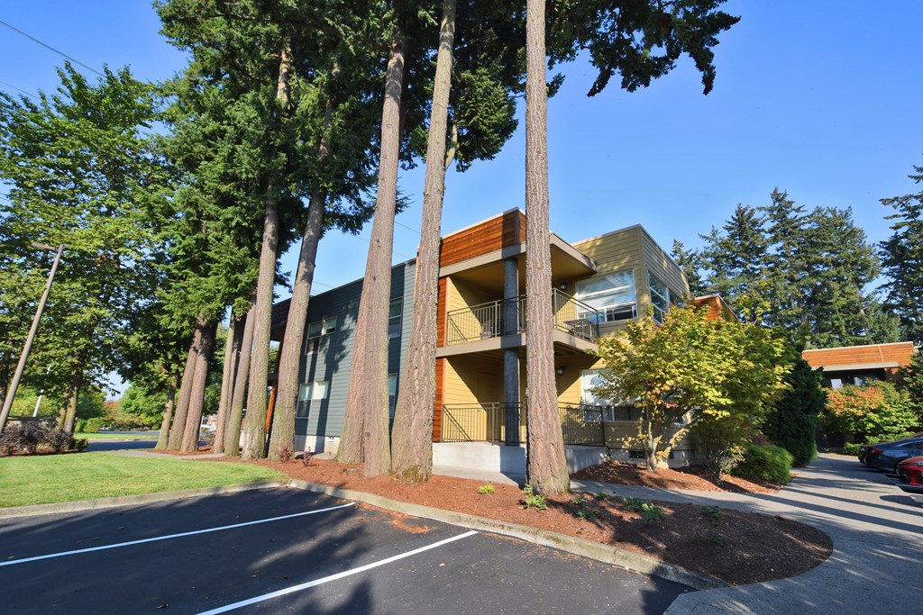 a yellow building with tall trees in front of it