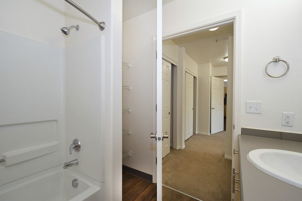 a bathroom with a shower and a sink and a hallway with a door to a