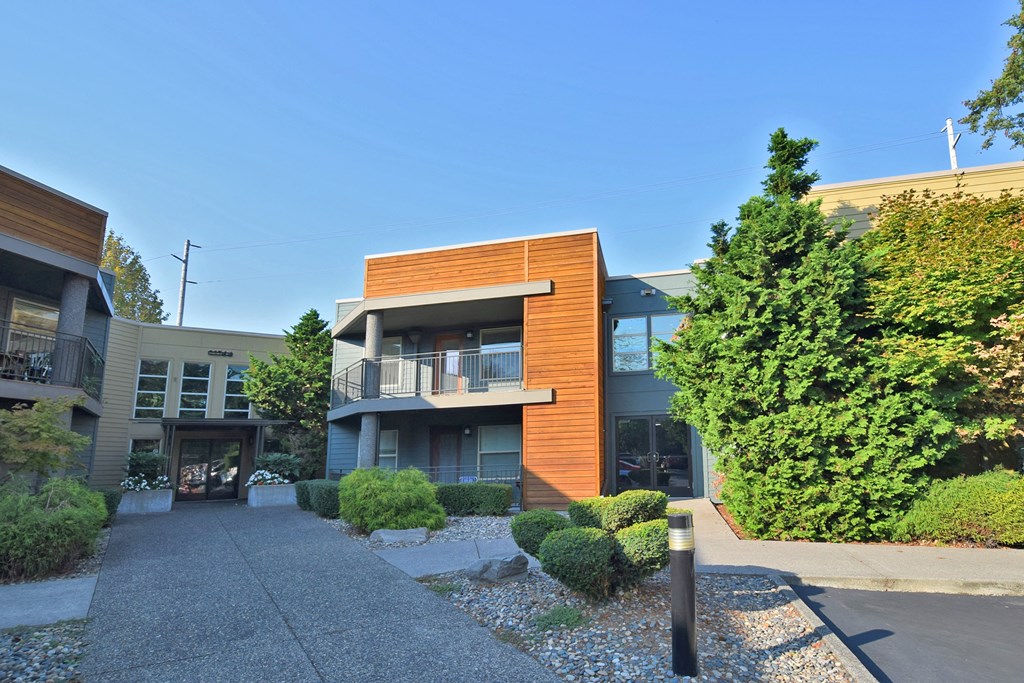 a view of the front of a building with a driveway and trees