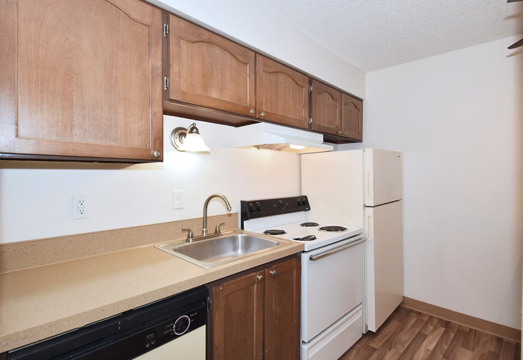 an empty kitchen with white appliances and wooden cabinets