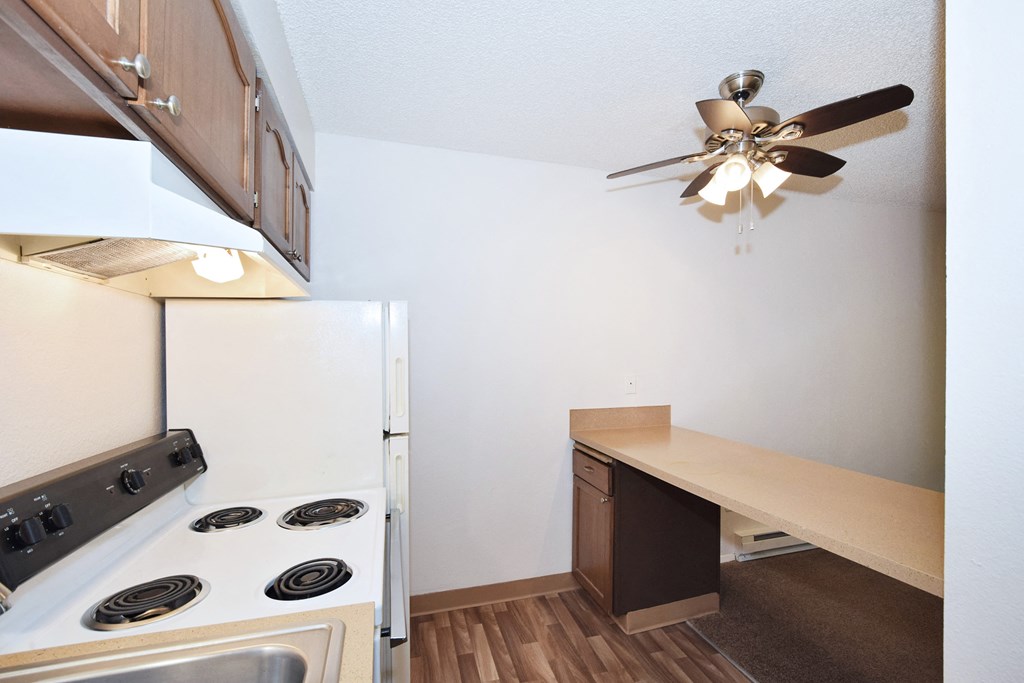 a kitchen with a stove refrigerator and a ceiling fan