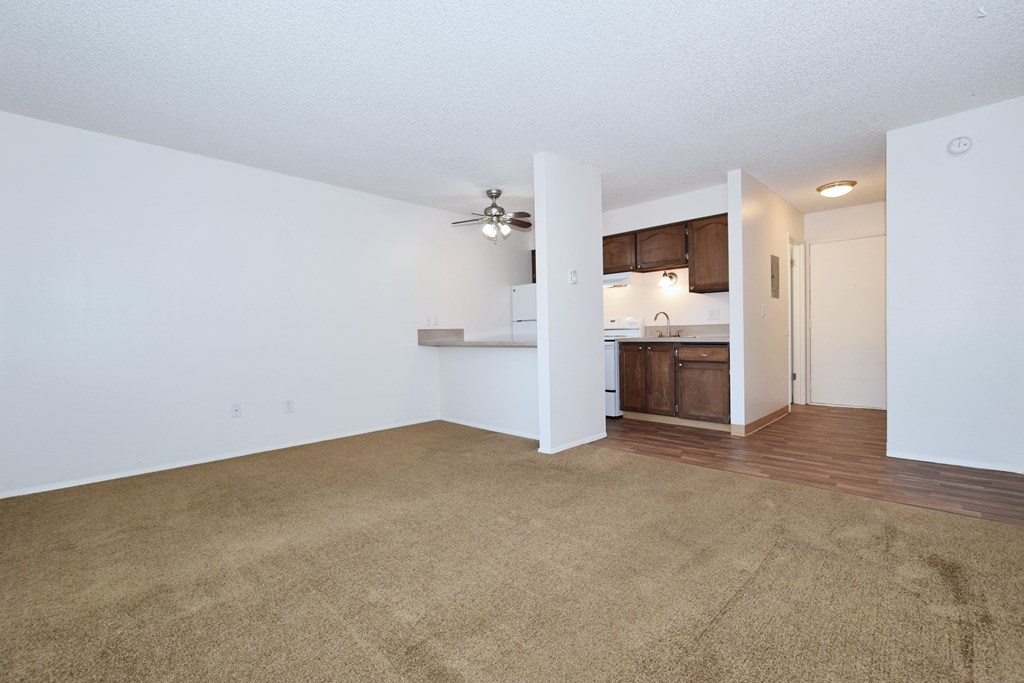 an empty living room and kitchen with a ceiling fan