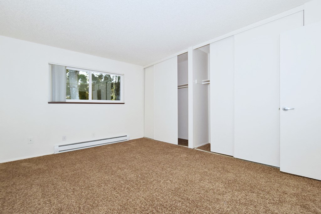 an empty room with carpet and white walls and a window