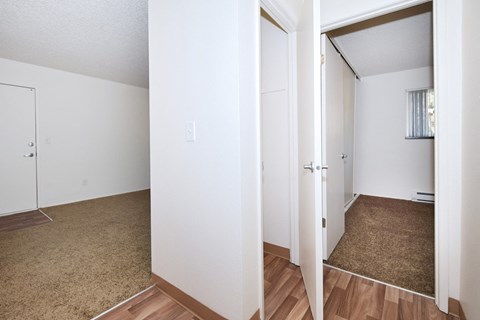 the living room and bedroom of an apartment with wood flooring and white walls