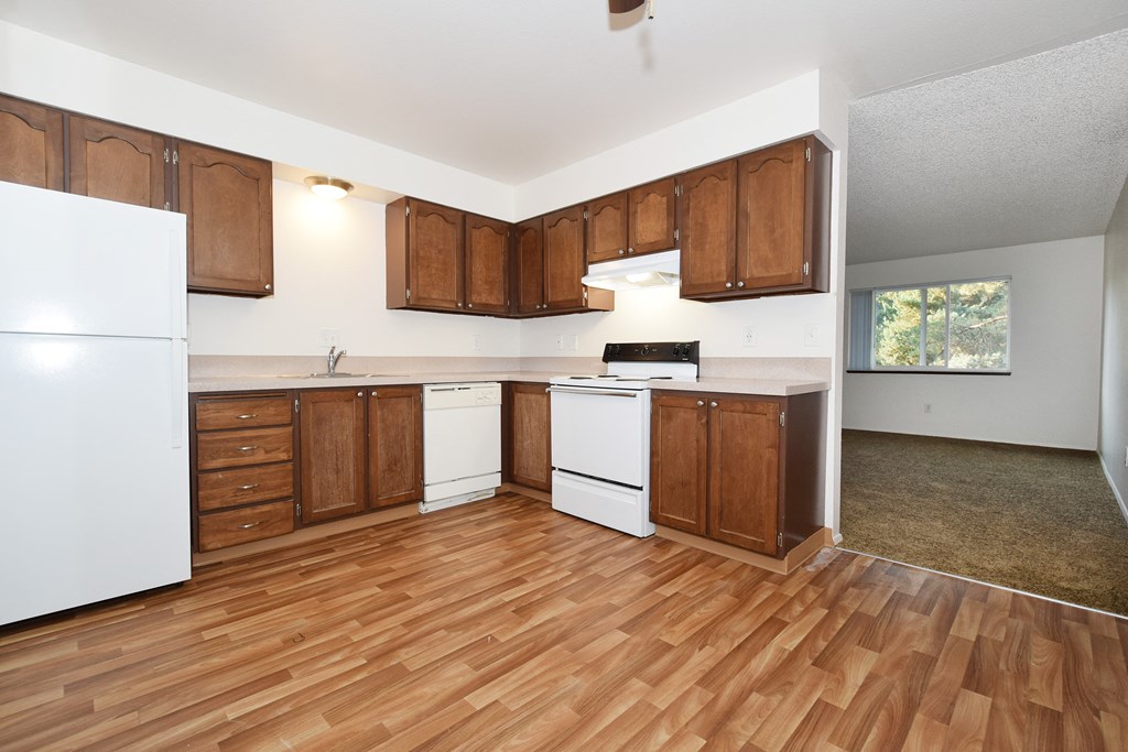 an empty kitchen with wooden floors and white appliances