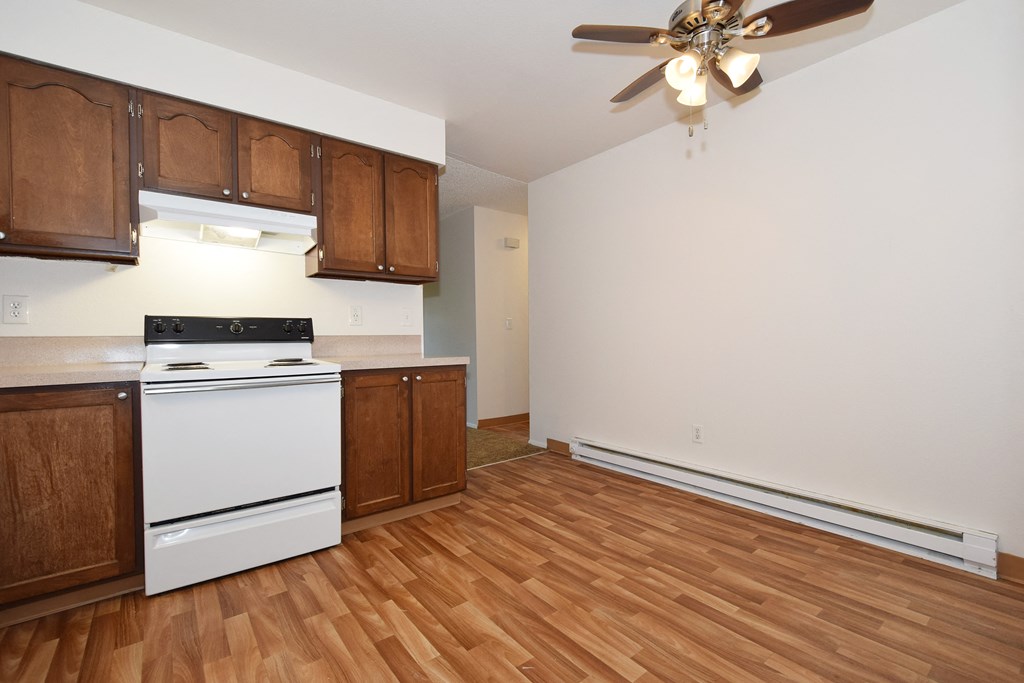 the view of a kitchen and living room with wood flooring and a ceiling fan