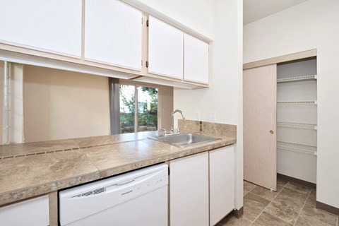 a kitchen with white cabinets and a sink and a dishwasher