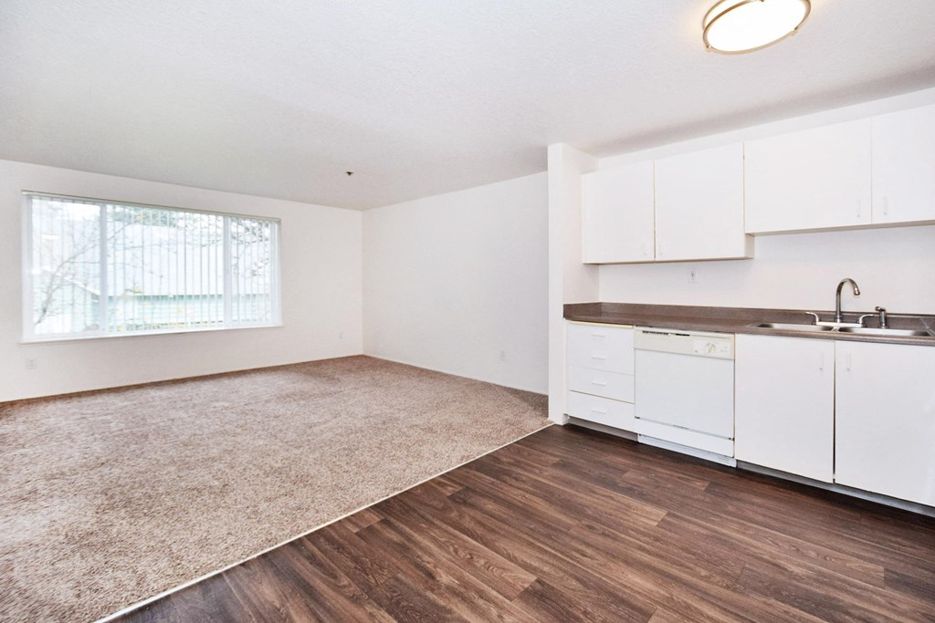 an empty kitchen with white cabinets and a sink and a window