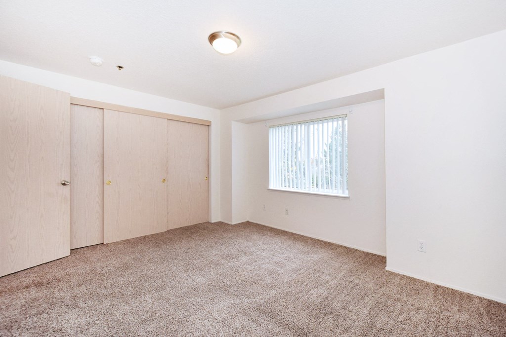 an empty living room with white walls and carpet and a window